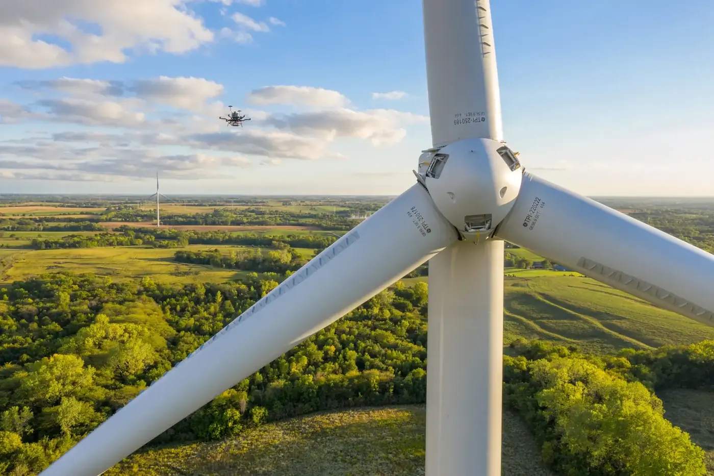 Drone flying beside a wind turbine above farmland
